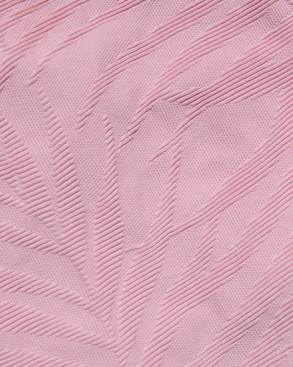 A close-up of light pink textured fabric with a raised leaf-like pattern.