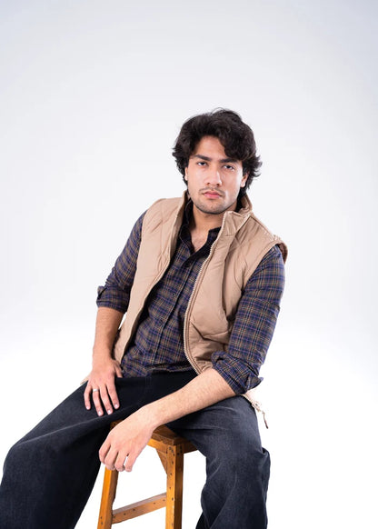 Men's beige quilted bubble jacket with stand collar, worn over plaid shirt sleeves