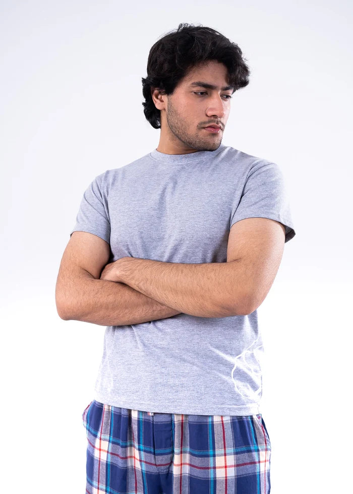 Men's grey melange T-shirt and blue-red plaid night pants, arms crossed