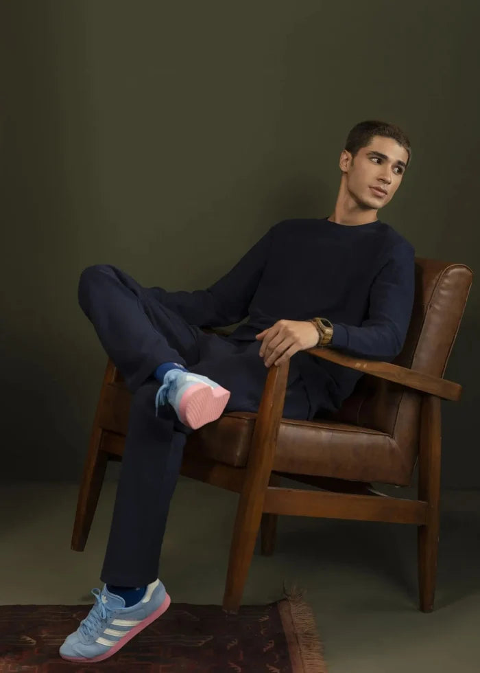 Navy crewneck sweatshirt, long sleeves, ribbed cuffs, worn with dark pants