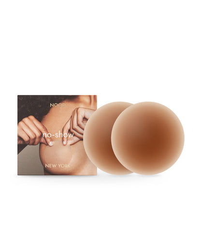 Off-model image of the NOOD No Show Adhesive Nipple Covers in bronze with the NOOD branded packaging box.