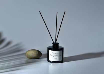 Black reed diffuser bottle with three dark reeds and label