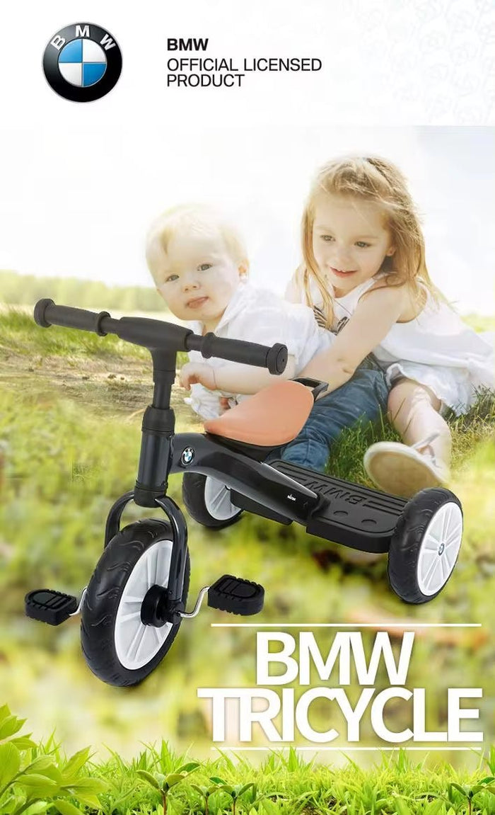 Children playing with a BMW tricycle in a grassy field, with the BMW logo visible.
