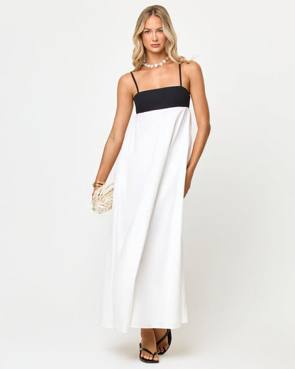 Front view of a model wearing the LSPACE Raveena Dress in black-cream, a maxi dress with a black square-neck bodice, spaghetti straps, and a flowing cream skirt.