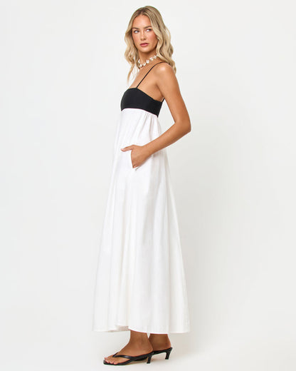 Side view of a model wearing the LSPACE Raveena Dress in black-cream, showing the empire-waist silhouette with a black bodice, spaghetti straps, and a flowing cream maxi skirt.