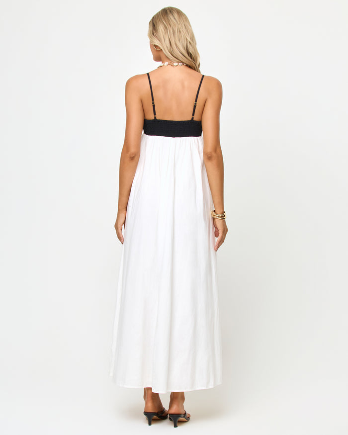 Back view of a model wearing the LSPACE Raveena Dress in black-cream, showing the adjustable spaghetti straps against the black bodice and the full flowing cream maxi skirt.