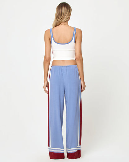Back full-length studio view of the Reset Tank in Cream-Chambray-Fig, a cream ribbed scoop-neck crop cami with chambray blue strap trim and burgundy color-block side panels, styled with chambray blue wide-leg stripe pants with burgundy side stripes and stripe trim at the ankle hem.