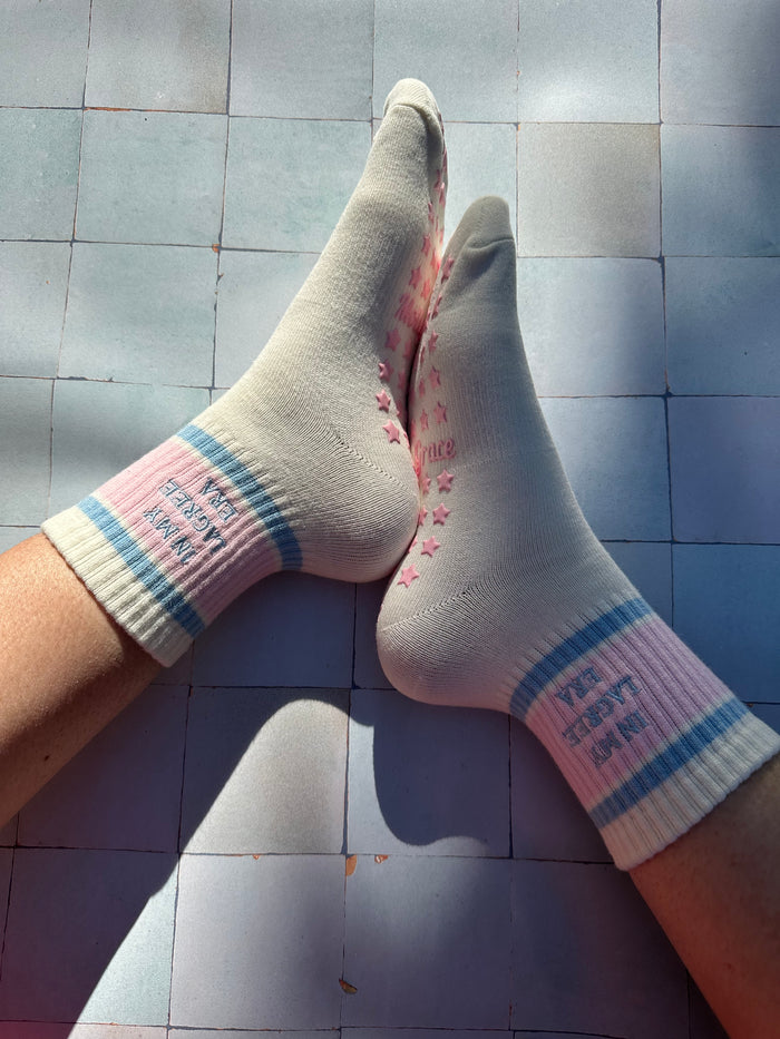 Cream pilates non slip grip sock with pink and blue stripes and pink star grips.  "in my lagree era" is embroidered on them. Used for Pilates, yoga, lagree and barre