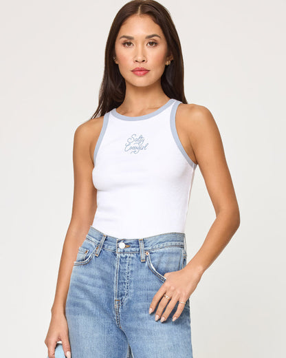 Front view of a model wearing the LSPACE Rewind Tank in salty cowgirl, a white ribbed tank top with blue contrast trim and a salty cowgirl script graphic on the chest, styled with high-waisted jeans.