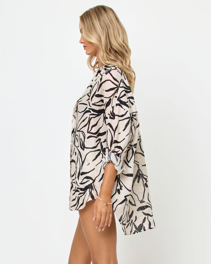 Side view of a model wearing the LSPACE Rio Tunic in heavy petal, showing the oversized linen silhouette with bold black botanical brushstroke print and three-quarter sleeves, styled with the matching Rio Short.