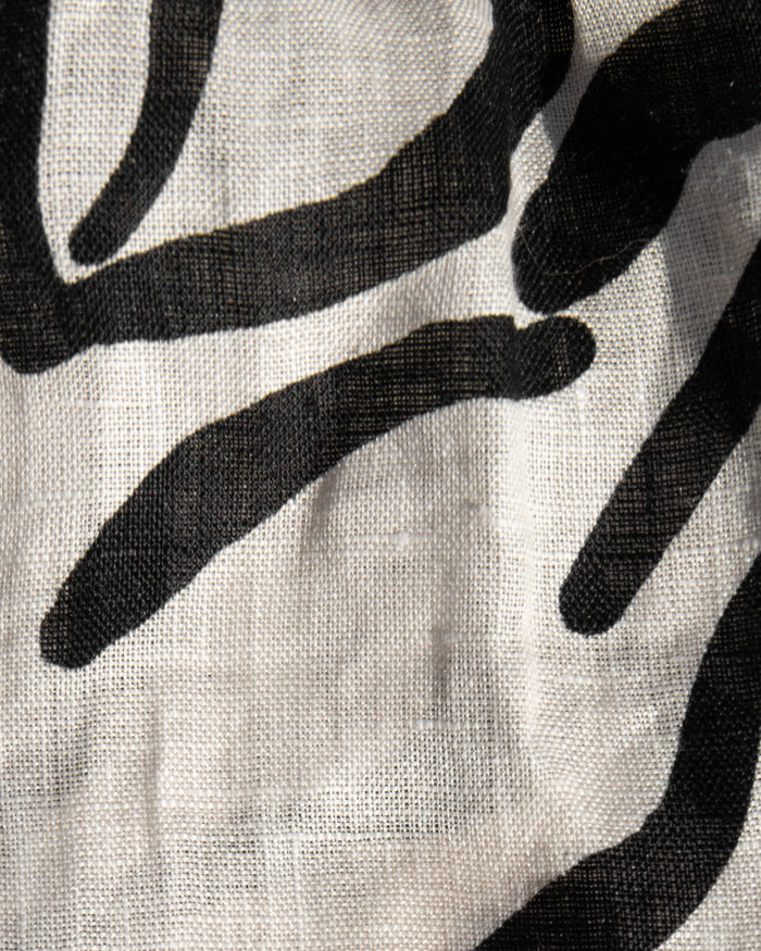 Close-up of the LSPACE Rio Tunic and Short in heavy petal, highlighting the linen fabric texture and bold black botanical brushstroke print on a cream background.