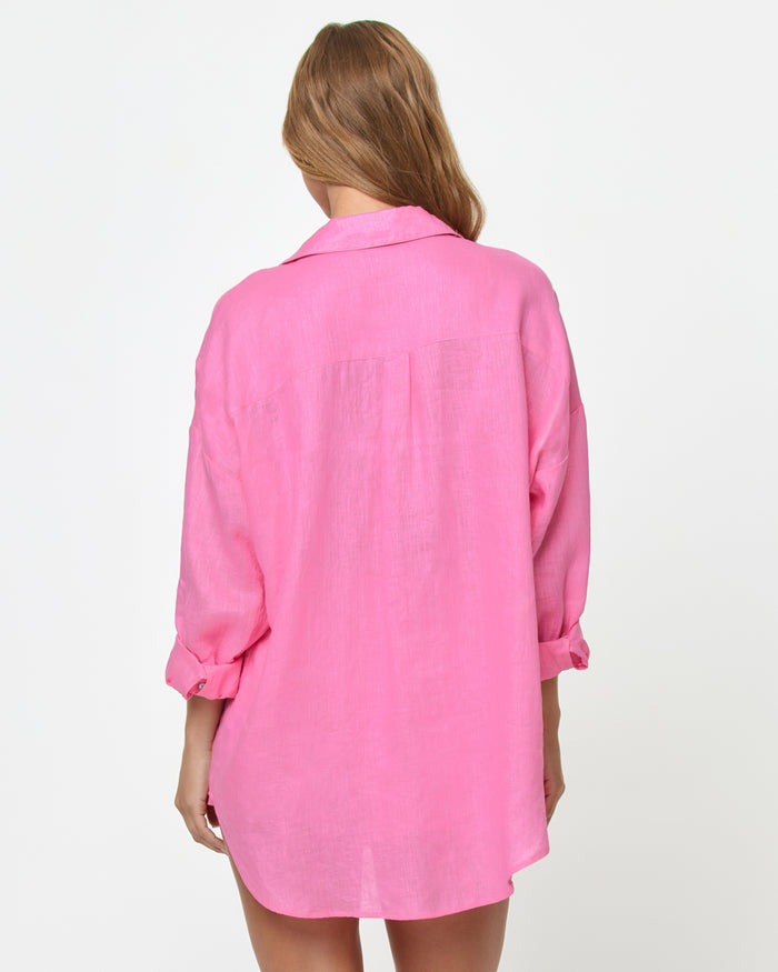 Back view of a model wearing the LSPACE Rio Tunic in hottest pink, showing the oversized linen button-up silhouette with three-quarter rolled sleeves and a relaxed fit.