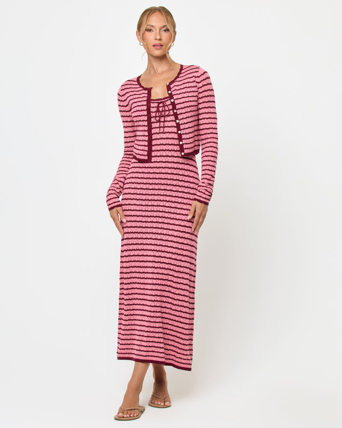 Front view of a model wearing the LSPACE Rosalie Cardigan in strawberry stripe, a cropped knit cardigan with pink and burgundy horizontal stripes and gold button closure, styled with the matching Rosalie Maxi dress.