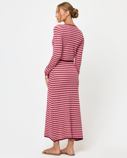 Back view of a model wearing the LSPACE Rosalie Cardigan in strawberry stripe, a cropped knit cardigan with pink and burgundy horizontal stripes, styled with the matching Rosalie Maxi dress.