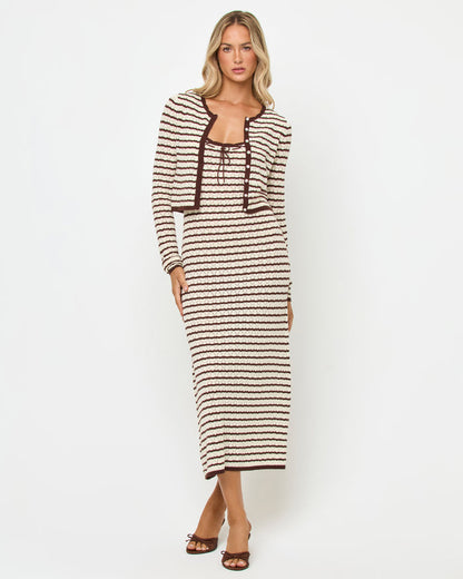 Front view of a model wearing the LSPACE Rosalie Maxi in cafe-cream, a fitted sleeveless knit maxi dress with cream and dark brown horizontal stripes and lace-up tie neckline, styled with the matching Rosalie Cardigan and brown heels.