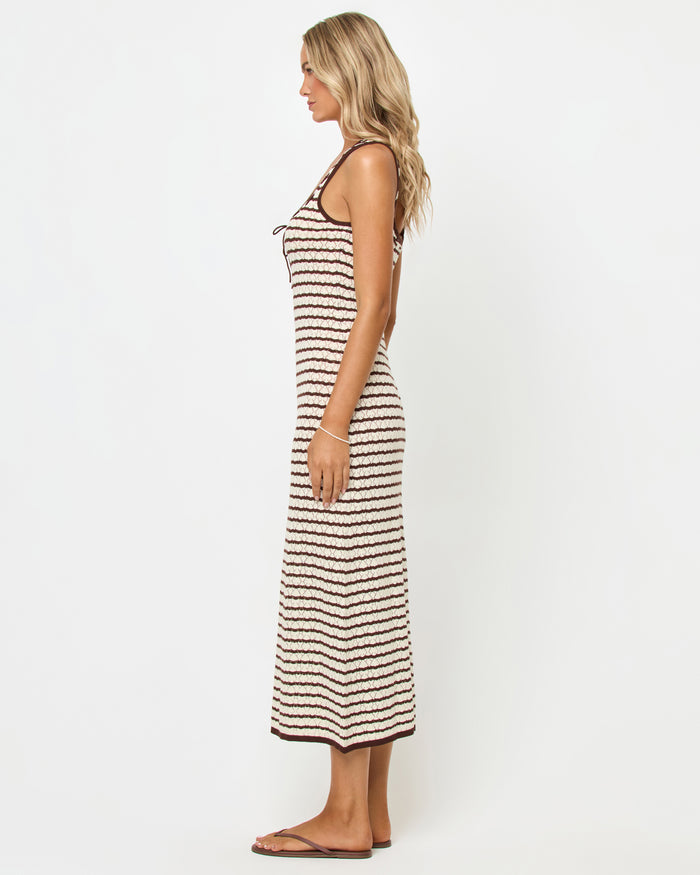 Side view of a model wearing the LSPACE Rosalie Maxi in cafe-cream, a fitted sleeveless knit maxi dress with cream and dark brown horizontal stripes, showing the slim silhouette and maxi length.