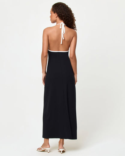 Back view of a model wearing the LSPACE Shea Maxi Dress in black-cream, showing the open back design with cream halter neck tie closure.