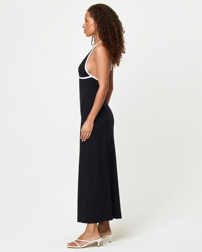 Side view of a model wearing the LSPACE Shea Maxi Dress in black-cream, showing the fitted silhouette and full length of the dress with cream contrast trim detail.
