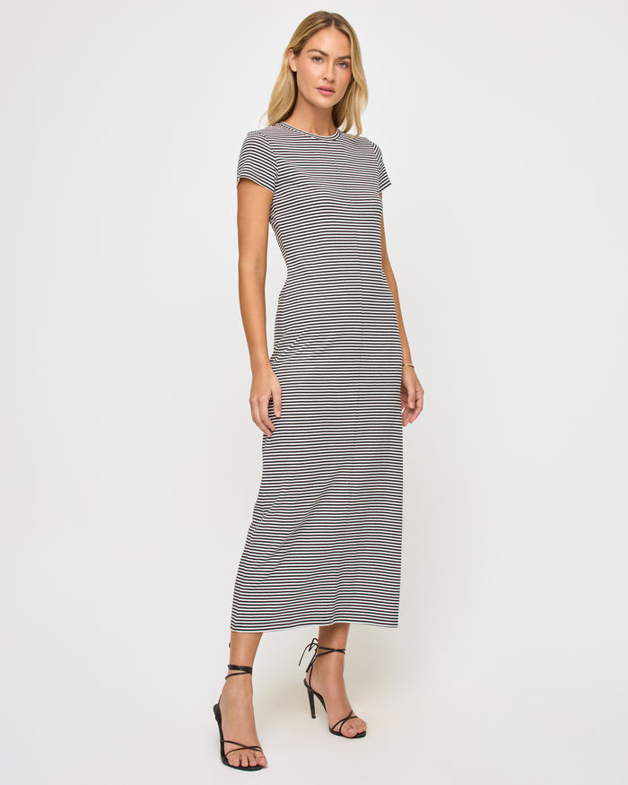 Angled front view of a model wearing the LSPACE Sloane Dress in black-cream, a fitted maxi dress featuring black and cream horizontal stripes, a crew neckline, and short sleeves.