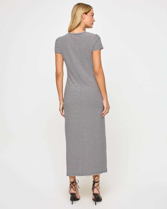 Back view of a model wearing the LSPACE Sloane Dress in black-cream, showing the fitted silhouette of the striped maxi dress with short sleeves.