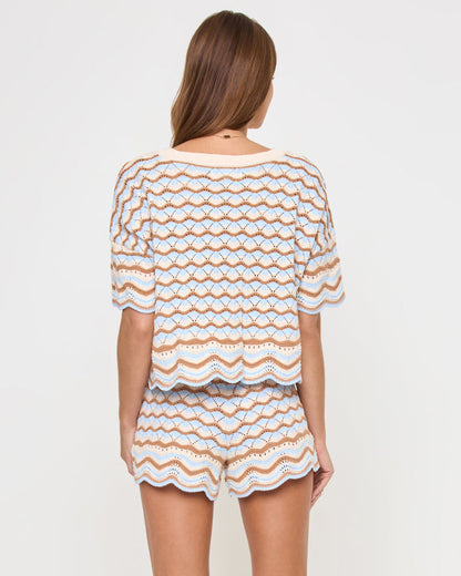 Back view of a model wearing the LSPACE Sunchaser Short in north shores, showing the scalloped hem and the wave pattern of the crochet shorts, styled with the matching knit top.