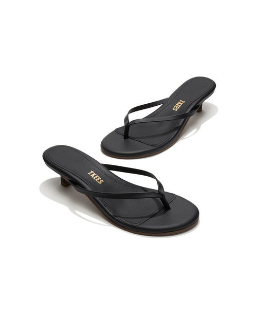 Angled view of both black sable leather TKEES Julia Kitten Heel thong sandals with TKEES logo.