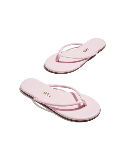 Angled view of both powder pink TKEES Tubular Lily flip flops with TKEES logo on footbed.