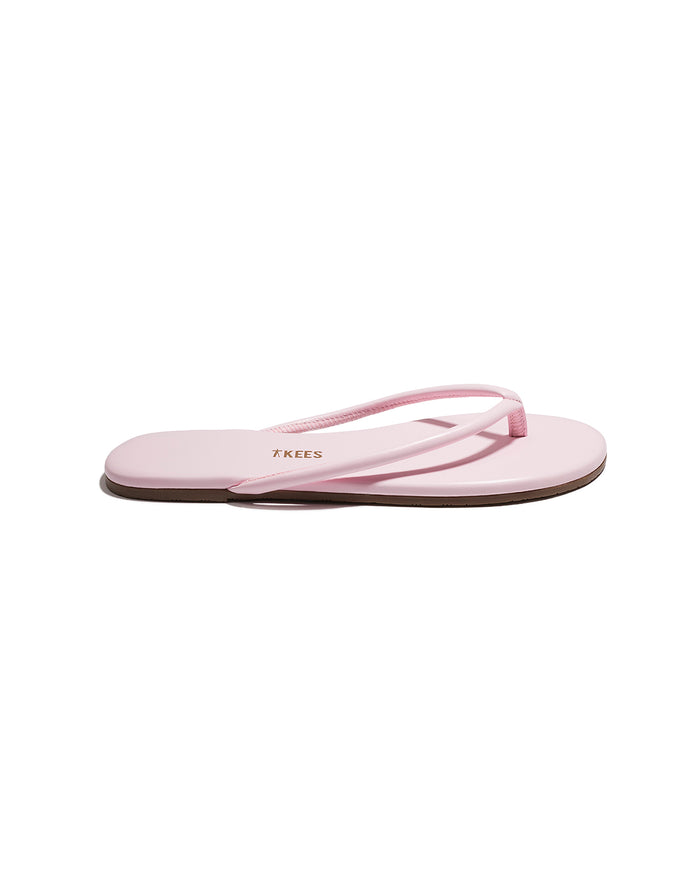 Side view of a single powder pink TKEES Tubular Lily flip flop with TKEES logo on footbed.