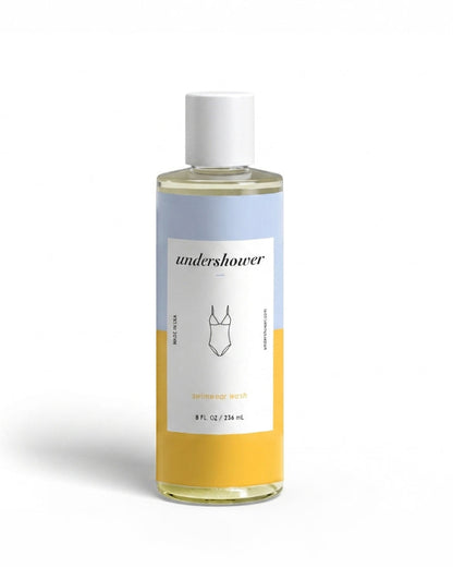 Front view of the Undershower Swimwear Detergent 8 fl. oz. clear glass bottle with blue and yellow label on a white background.