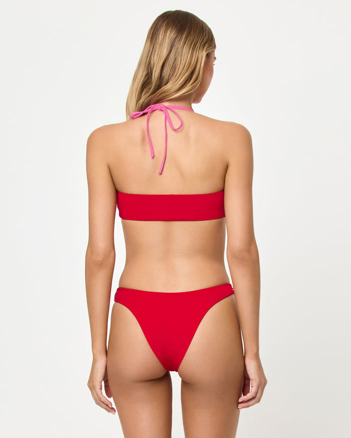 Back view of a model wearing the LSPACE Lipstick Red Sweetheart Vega Bikini Bottom with a matching color-blocked bralette top.
