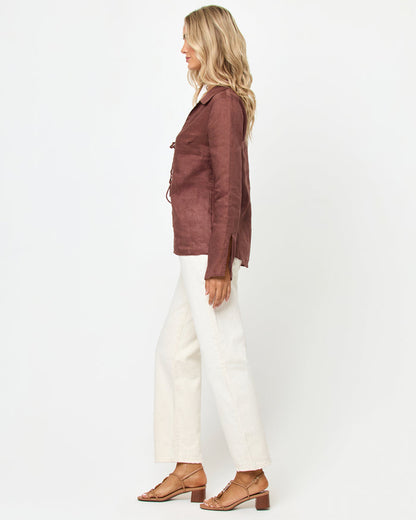 Side view of a model wearing the LSPACE Venice Shirt in cafe, showing the linen construction, tie front closures, and side slits, styled with white wide-leg pants.