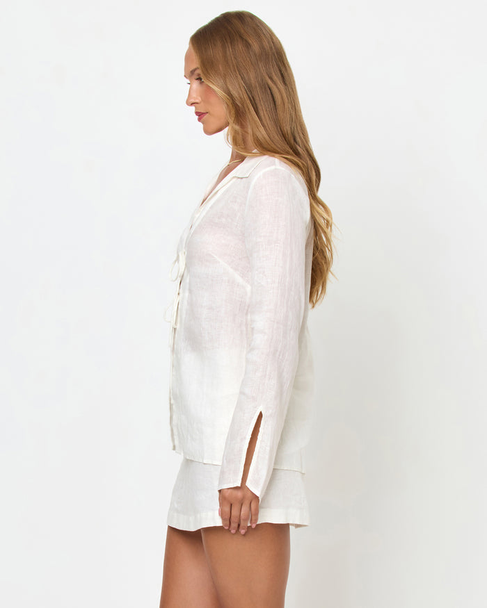 Side view of a model wearing the LSPACE Venice Shirt in white, showing the linen construction, tie front closures, and side slits, styled with the matching Venice Skort.