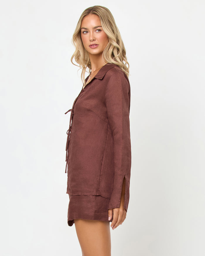 Side view of a model wearing the LSPACE Venice Skort in cafe, showing the linen A-line mini silhouette and side hem, styled with the matching Venice Shirt in cafe.