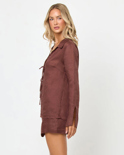 Side view of a model wearing the LSPACE Venice Skort in cafe, showing the linen A-line mini silhouette and side hem, styled with the matching Venice Shirt in cafe.