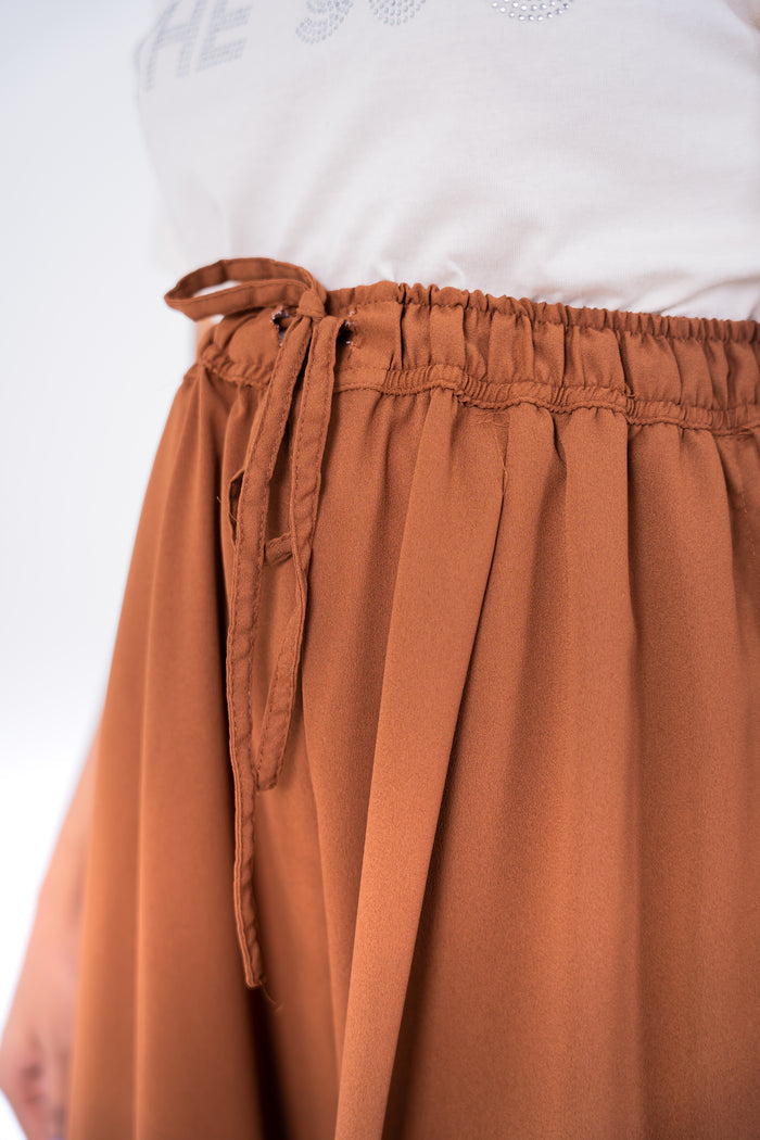 Brown elastic-waist trousers with drawstring tie and gathered waistband detail