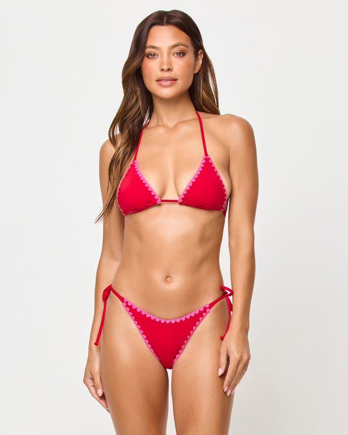 Front view of model wearing the LSPACE Zahra Bikini Top in lipstick red, a triangle halter top with pink sweetheart scallop trim, paired with matching Zahra Bikini Bottom.